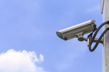 Mavi gökyüzü arkaplanındaki güvenlik kamerası