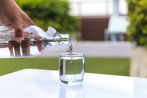 Стакан воды с бутылкой на столе — стоковое фото