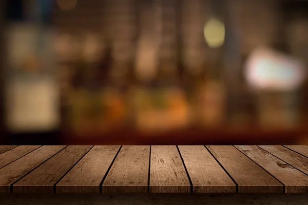 Dřevěný stůl s výhledem na bar pozadí rozmazané nápoje — Stock fotografie