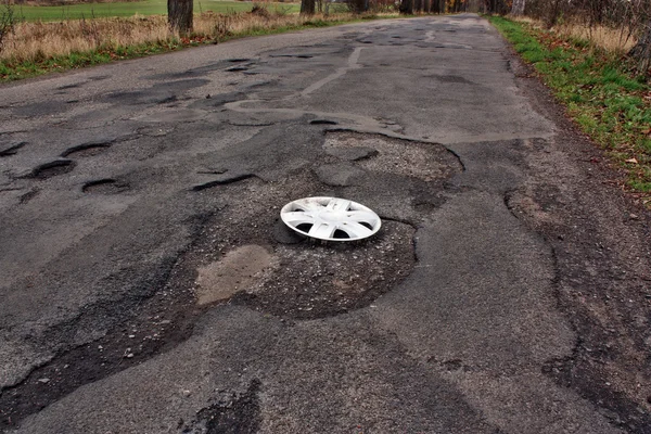 Wheel cover clipped on the damaged road — Stock Photo, Image