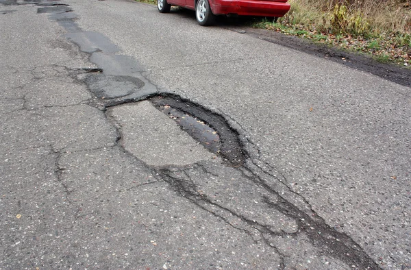 Car and holes in the asphalt — Stock Photo, Image