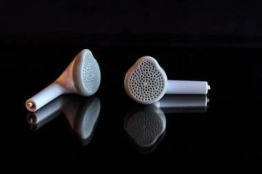 Siyah camlara yansıyan iki ayrı beyaz kulaklık.