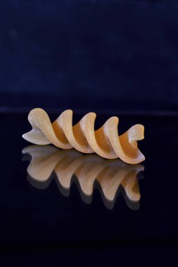Fusilli makarna yakın plan, siyah arkaplan üzerine yansıtılır
