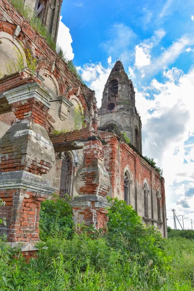 part of a ruined church with a bell tower overgrown with grass against the background of a cloudy sky, close-up