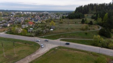 Yol, araba ve evleri olan kırsal bir arazinin havadan görünüşü.