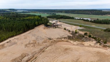 Aerial view of a sand quarry surrounded by forests and fields.
