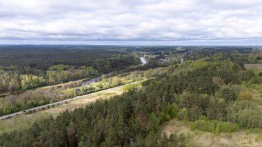 Bereketli bir yeşil orman manzarası, dolambaçlı bir nehir ve bulutlu bir gökyüzü..