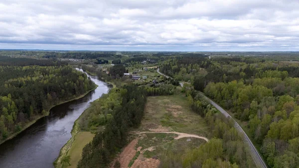 Bereketli yeşil manzaralı, dolambaçlı bir nehir ve dağınık evler..