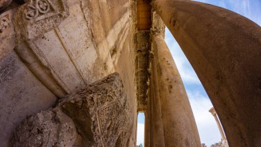 Mavi gökyüzüne karşı antik taş sütunların ve süslemelerin alçak açılı görüntüsü. Baalbek, Lübnan.