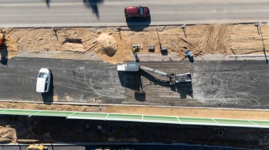 Araçlar ve işçilerle yol yapımının havadan görüntüsü.