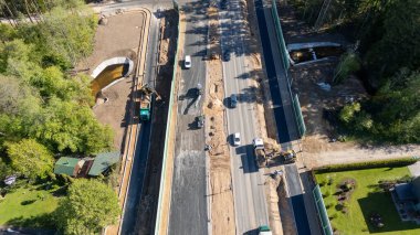 Bir yol şantiyesinin havadan görünüşü. Makineler, yeni yerleştirilmiş asfalt ve çevreleyen yeşillikler.