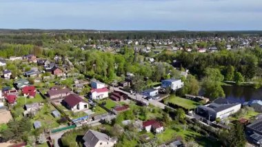 Ağaçları ve evleri olan yemyeşil bir banliyö bölgesinin havadan görünüşü.