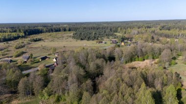 Dağınık evleri ve sık ormanları olan kırsal bir arazinin havadan görünüşü.