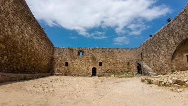 Mavi gökyüzü ve bulutları olan antik taş kale avlusu. Trablus Kalesi, Lübnan.