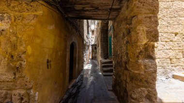 Kırsal duvarları ve ahşap kirişleri olan dar taştan dar bir sokak. Lübnan, Trablus.