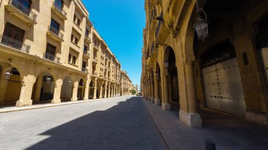 Temiz mavi gökyüzünün altında tarihi mimarisi ve kemerleri olan boş bir sokak. Lübnan, Beyrut.