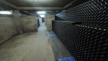 Yeraltında raflarda şarap şişeleri olan loş bir şarap mahzeni..