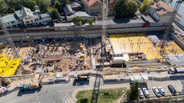 Vinçleri ve makineleri olan büyük bir inşaat alanının havadan görüntüsü.