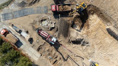Kamyonları ve kazıcıları olan bir inşaat alanının havadan görüntüsü.