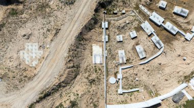 Beton temelleri ve yolları olan bir inşaat alanının havadan görünüşü.