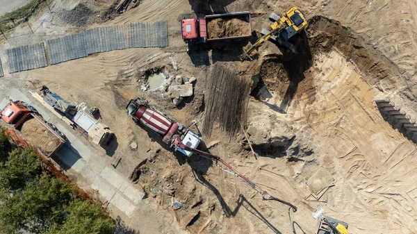 Kamyonları ve kazıcıları olan bir inşaat alanının havadan görüntüsü.