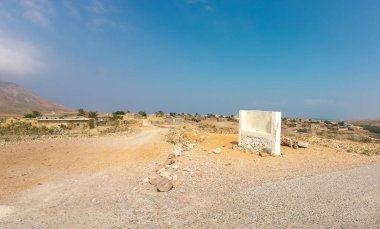 Toprak yolu, dağınık evleri ve açık mavi gökyüzü olan çöl manzarası..
