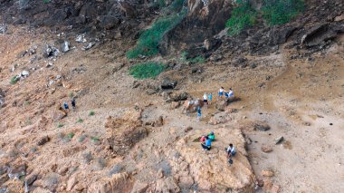 Kayalık bir arazide seyrek bitki örtüsü olan yürüyüşçülerin hava manzarası. Sokotra, Yemen.