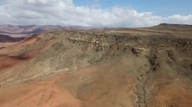 Bulutlu gökyüzü altında engebeli kurak dağların ve çöl platosunun havadan görünüşü katmanlı tepeler ve erozyon çizgileri geniş panoramik manzara. Sokotra, Yemen.