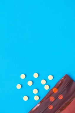 İlaç çantasından dökülen bir hap. Çeşitli hastalıkların tedavisinde kullanılan pek çok çeşit ilaç vardır. Mavi arkaplan