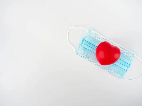 Coração Vermelho Uma Máscara Azul Fundo Branco Aumentando Preocupação Durante — Fotografia de Stock
