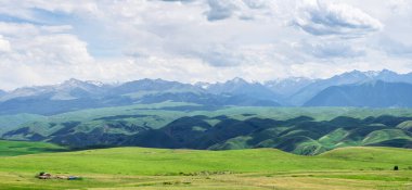 Bulutlu bir günde otlaklar ve dağlar. Çin, Xinjiang 'da çekildi..