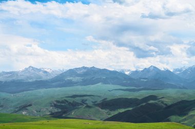 Bulutlu bir günde otlaklar ve dağlar. Çin, Xinjiang 'da çekildi..