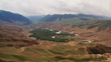 Dağ zirveleri ve çayırlar beyaz bulutların altında..