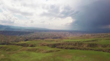 Dağ zirveleri ve çayırlar beyaz bulutların altında..
