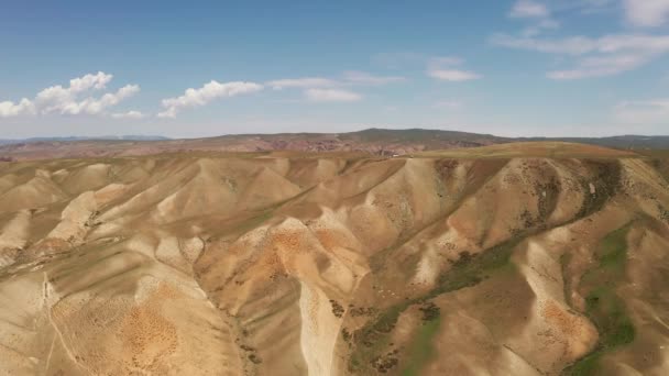 Montañas onduladas bajo cielo azul y nubes blancas. — Vídeo de stock