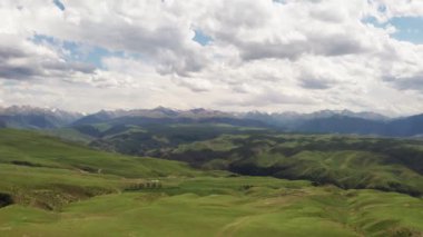 Dağ zirveleri ve çayırlar beyaz bulutların altında. Kalajun otlağında hava fotoğrafı, xinjiang, Çin.