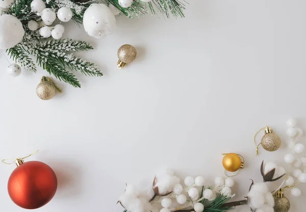 Beyaz arka planda Noel ağacı dallarıyla, oyuncaklarla ve dekorasyonlarla yatıyordu.