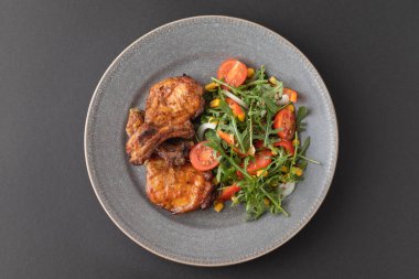 Tabakta taze sebze salatasıyla nefis kızarmış pirzola. Üst Manzara. Koyu masa.