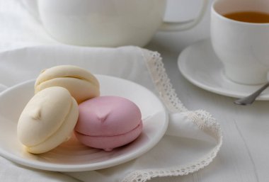 Beyaz ahşap masada bir fincan çayla tatlı marşmelovlar. Yakın görünüm.