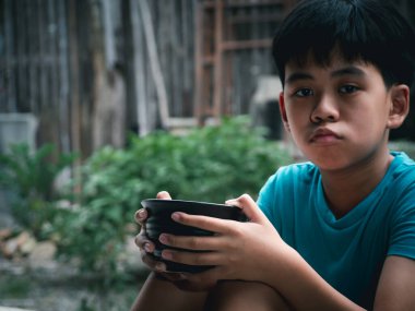 Aç çocuk elinde boş siyah bir kâse tutuyor mutsuz beslenme için yemek bekliyor. Şehirdeki gezginlerden yiyecek bağışı istiyorlar. Sokakta dilenen kimliği belirsiz evsiz çocuk..