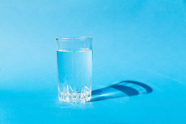 Fresh clean water in a glass on a blue background