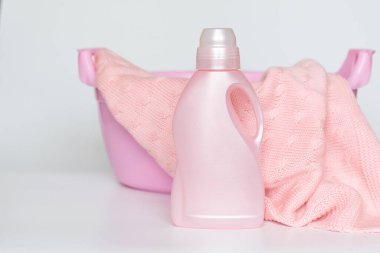 Örgü örülmüş bir battaniyeyle leğenin arka planında yünlü şeyleri yıkamak için deterjan olan bir şişe.. 