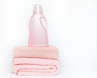 Yünlü şeyleri yıkamak için deterjanı olan pembe bir şişe örülmüş battaniyelerin üzerinde bulunur.. 