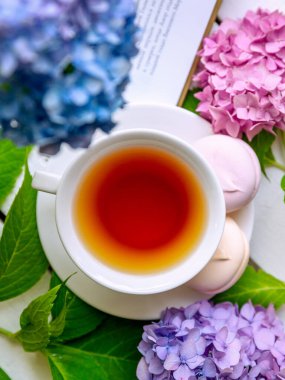 Ortanca çiçekleriyle çevrili bir fincan siyah çay.