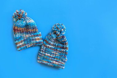 Yakında sonbahar geliyor. Modaya uygun mavi örülü şapkalar mavi arka planda