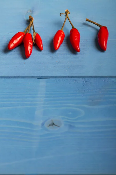 Rote Chilischoten auf blauem Holzhintergrund — Stockfoto
