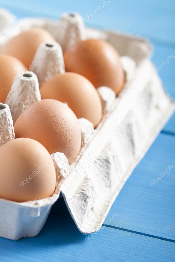 Eggs in the package on blue wooden table