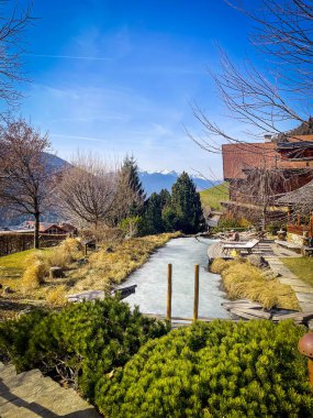 Donmuş açık hava yüzme havuzu güneşlenme alanı ve kar kaplı dağlar Luson, İtalya 'da açık mavi bir gökyüzü altında