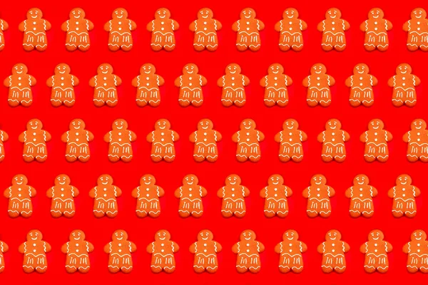 Colorful Gingerbread man pattern on bright red festive background. Tasty homemade Christmas gingerbread man with sugar glaze on bright red festive background. Close up