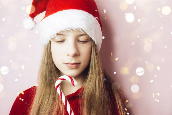 Smiling beautiful girl with long hair in fluffy Santa Claus hat on a pink background. Royalty Free Stock Photos